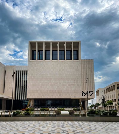 The geometric architecture of M7 and hexagonal tiled flooring against a cloudy Doha sky