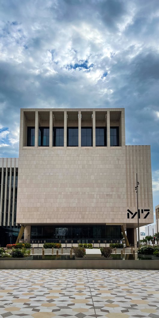 The geometric architecture of M7 and hexagonal tiled flooring against a cloudy Doha sky