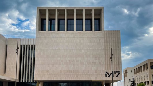 The geometric architecture of M7 and hexagonal tiled flooring against a cloudy Doha sky