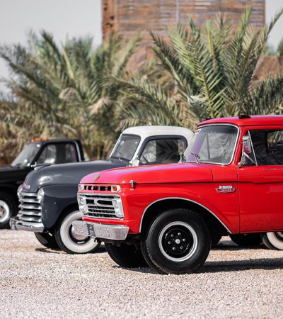 A row of classic cars parked in bright daylight for the Mal Lawal exhibition