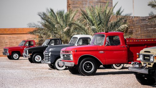 A row of classic cars parked in bright daylight for the Mal Lawal exhibition