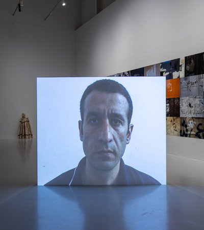 A projection of the artist, Taysir Batniji's face, in the middle of a gallery space.