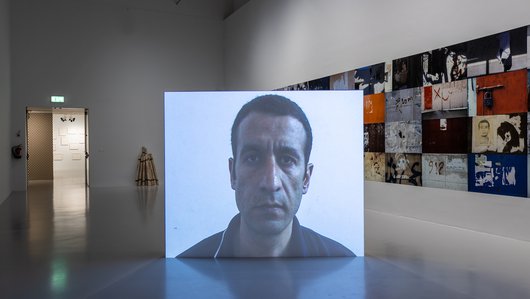 A projection of the artist, Taysir Batniji's face, in the middle of a gallery space.