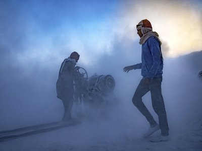 Two men stand in a dust filled landscape.