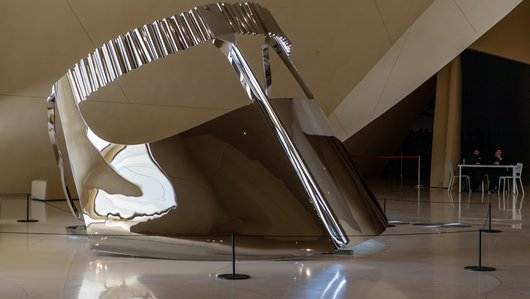 Large-scale shiny silver metallic sculpture depicting a 'niqab', a traditional face covering