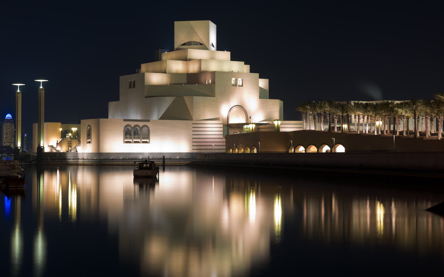 View of the Museum of Islamic Art illuminated at nighttime with its reflection in the surrounding water