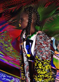 A young girl with yellow lipstick, stands in profile, wearing brightly coloured textiles against a colourful background.