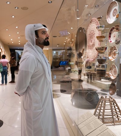 Qatari man viewing the National Museum of Qatar gallery while listening to an audio guide tour of the collection