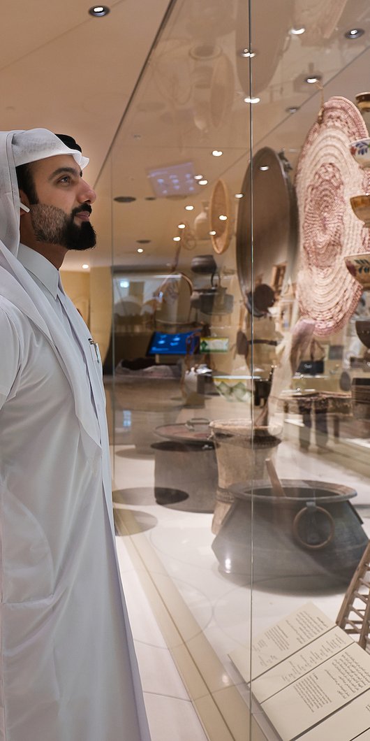 Qatari man viewing the National Museum of Qatar gallery while listening to an audio guide tour of the collection