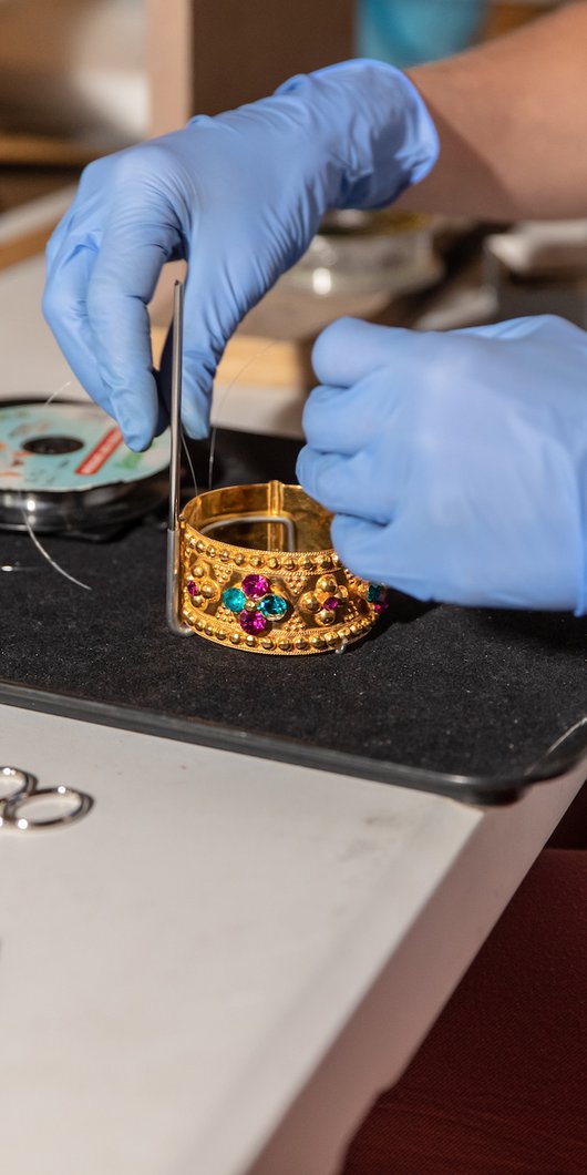 Conservator handling a gold bracelet