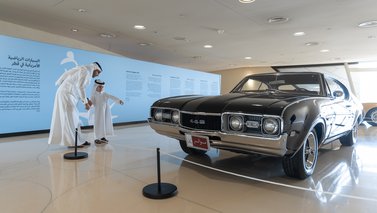 A shot of a father and son in Thobe looking the Oldsmobile 442 muscle car