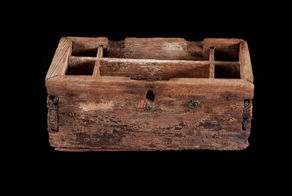 The exterior of a pearl box, made of wood, against a black background