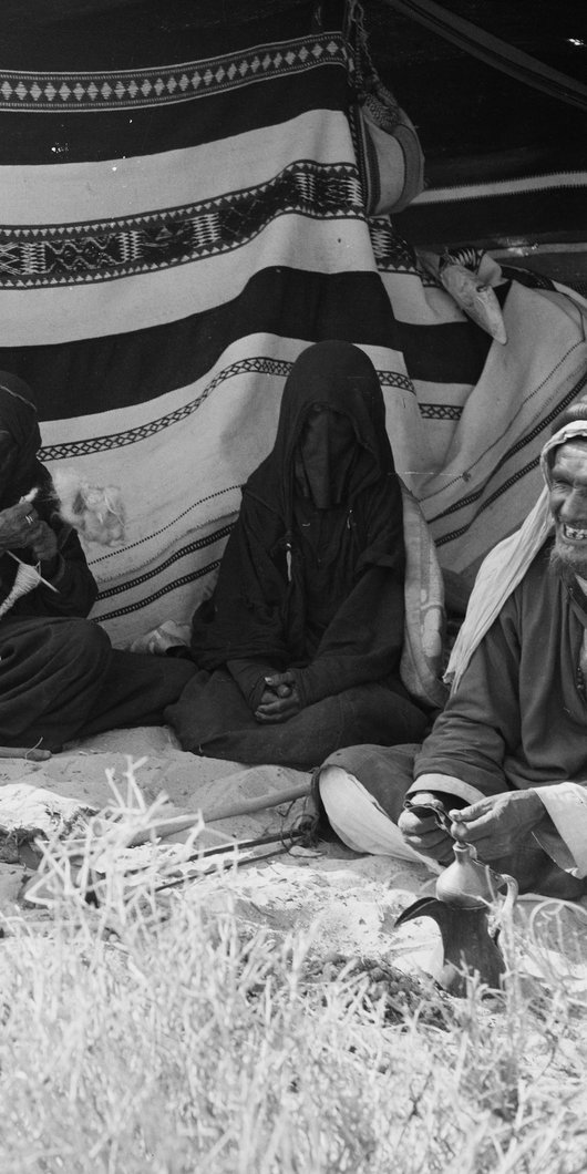 Three women spinning yarn inside a tent with an old man sitting next to them