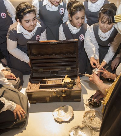 Students observing a man handling an old pearl diving kit