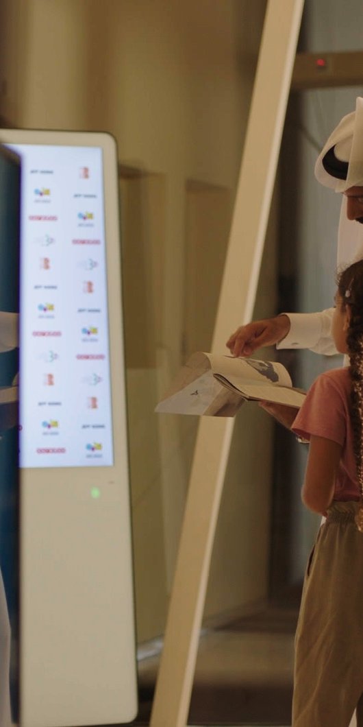 Qatari man and his daughter browsing the catalogue of the National Museum of Qatar