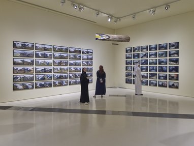 A gallery space showcasing a selection of landscape photography between two walls.