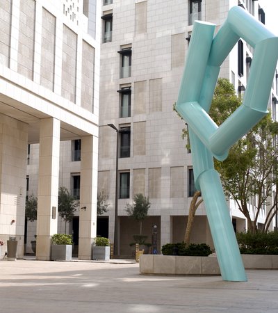 A woman walking past a large light blue pipe sculpture.