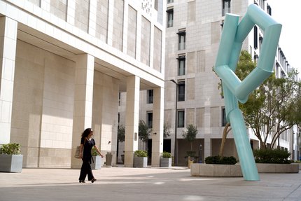 A woman walking past a large light blue pipe sculpture.