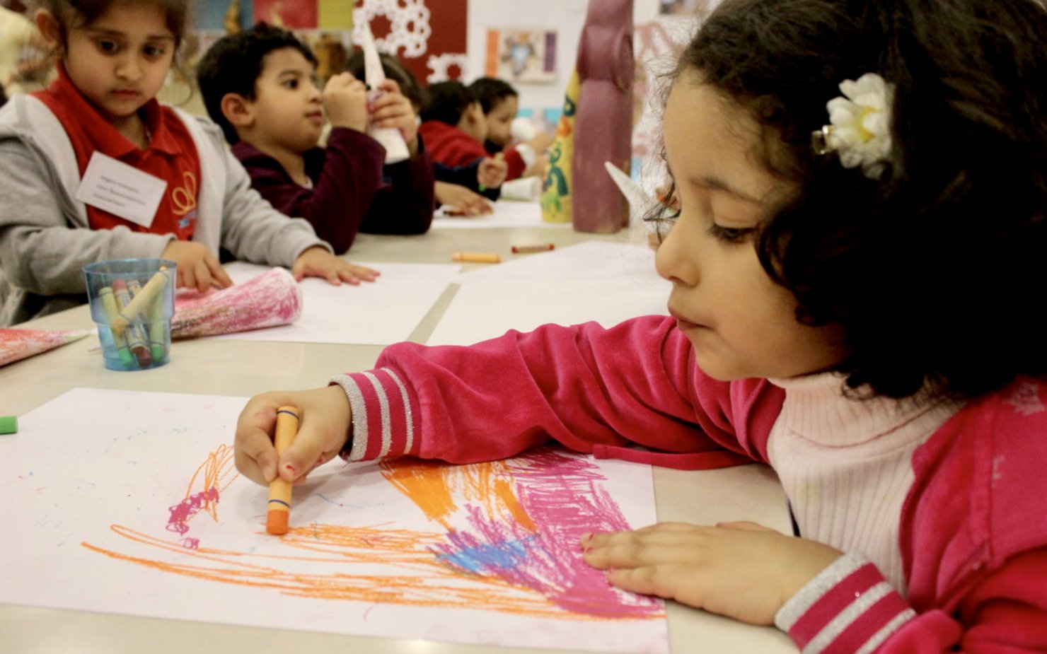 A group of children at a drawing workshop with scattered crayons and papers on the table