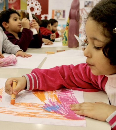 A group of children at a drawing workshop with scattered crayons and papers on the table