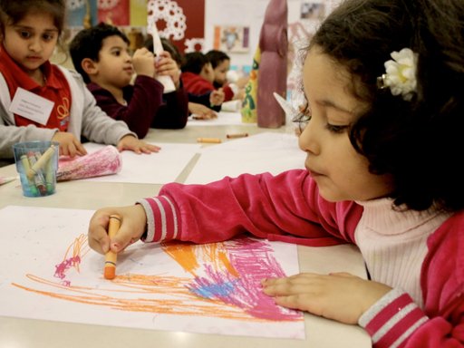 A group of children at a drawing workshop with scattered crayons and papers on the table