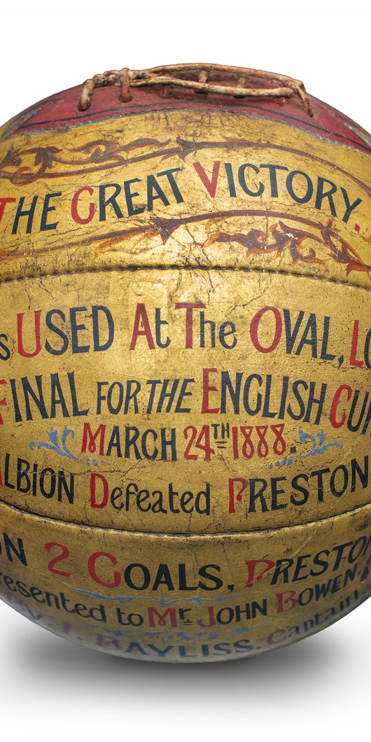 A golden coloured football with text that reads 'This ball was used at the Oval, London, in the final for the English Cup, March 24th 1888.