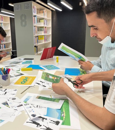 Four young men sit around a table with paper clippings of different sports.