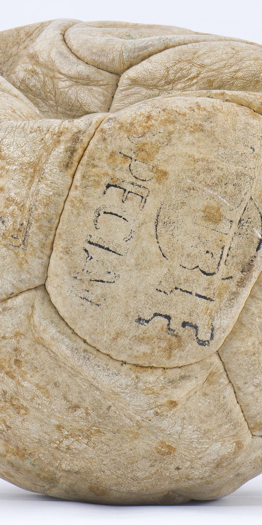 A football made of worn white leather with barely legible print.