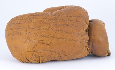 Penned annotations on a caramel leather glove, detailing boxing wins credited to Muhammad Ali.