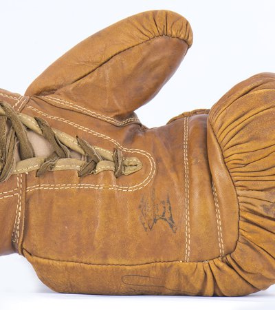 A camel coloured, aged, leather boxing glove lies on its side.