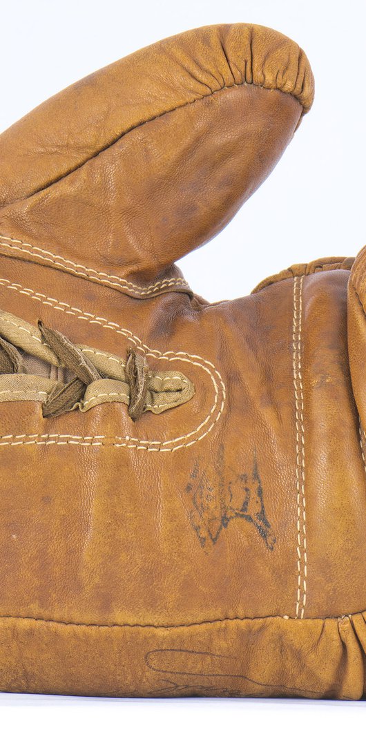 A camel coloured, aged, leather boxing glove lies on its side.