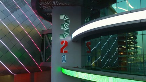 An image of neon lights highlighting the QOSM 3-2-1 signage