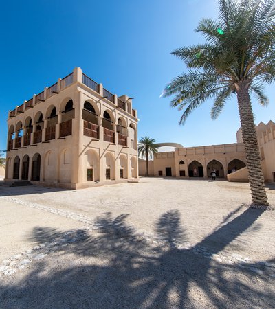 Restored historic palace with arches and sand coloured buildings in the background