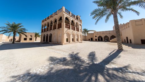 Restored historic palace with arches and sand coloured buildings in the background