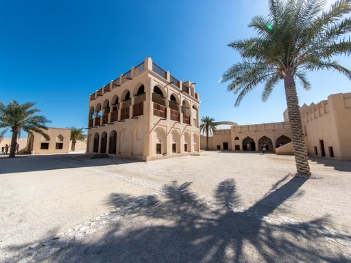 Restored historic palace with arches and sand coloured buildings in the background