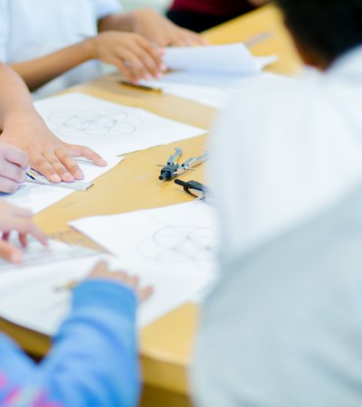 A group of children circled around a table, sketching out geometric shapes