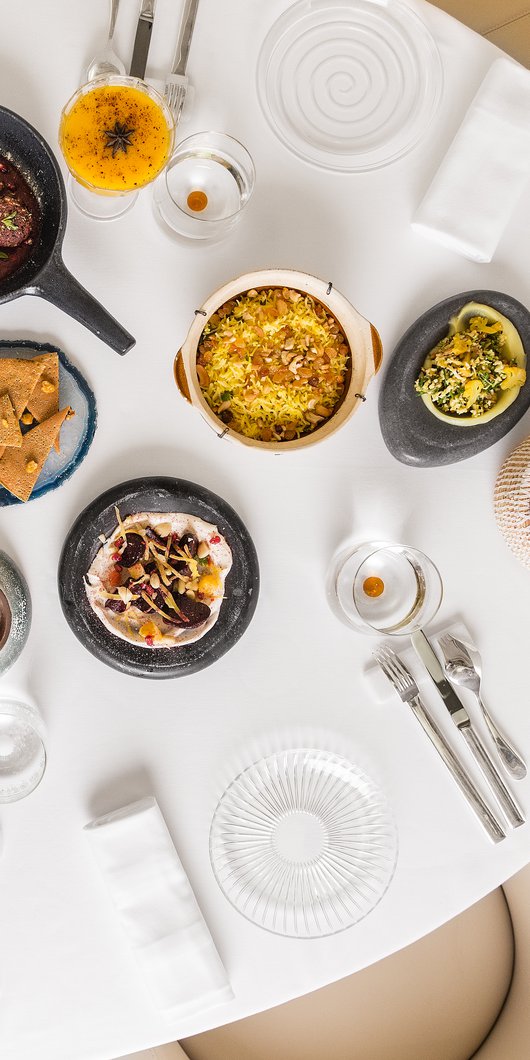 An view of a restaurant table seen from overhead with many colourful plates of traditional foods displayed