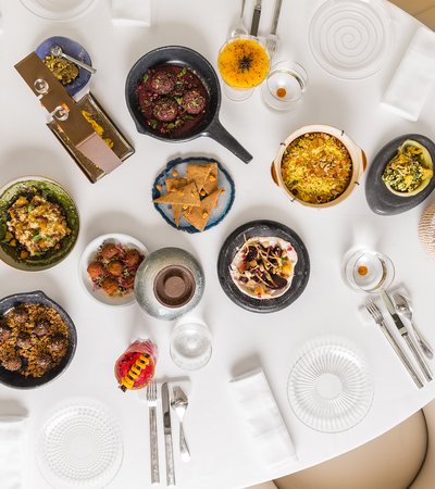 An view of a restaurant table seen from overhead with many colourful plates of traditional foods displayed