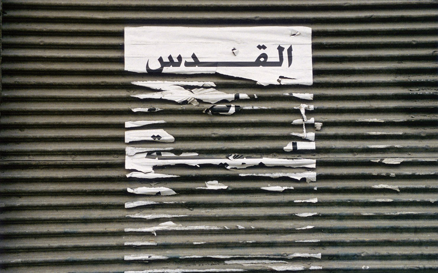 Picture of shredded paper on a textured background with the word Al Quds in Arabic