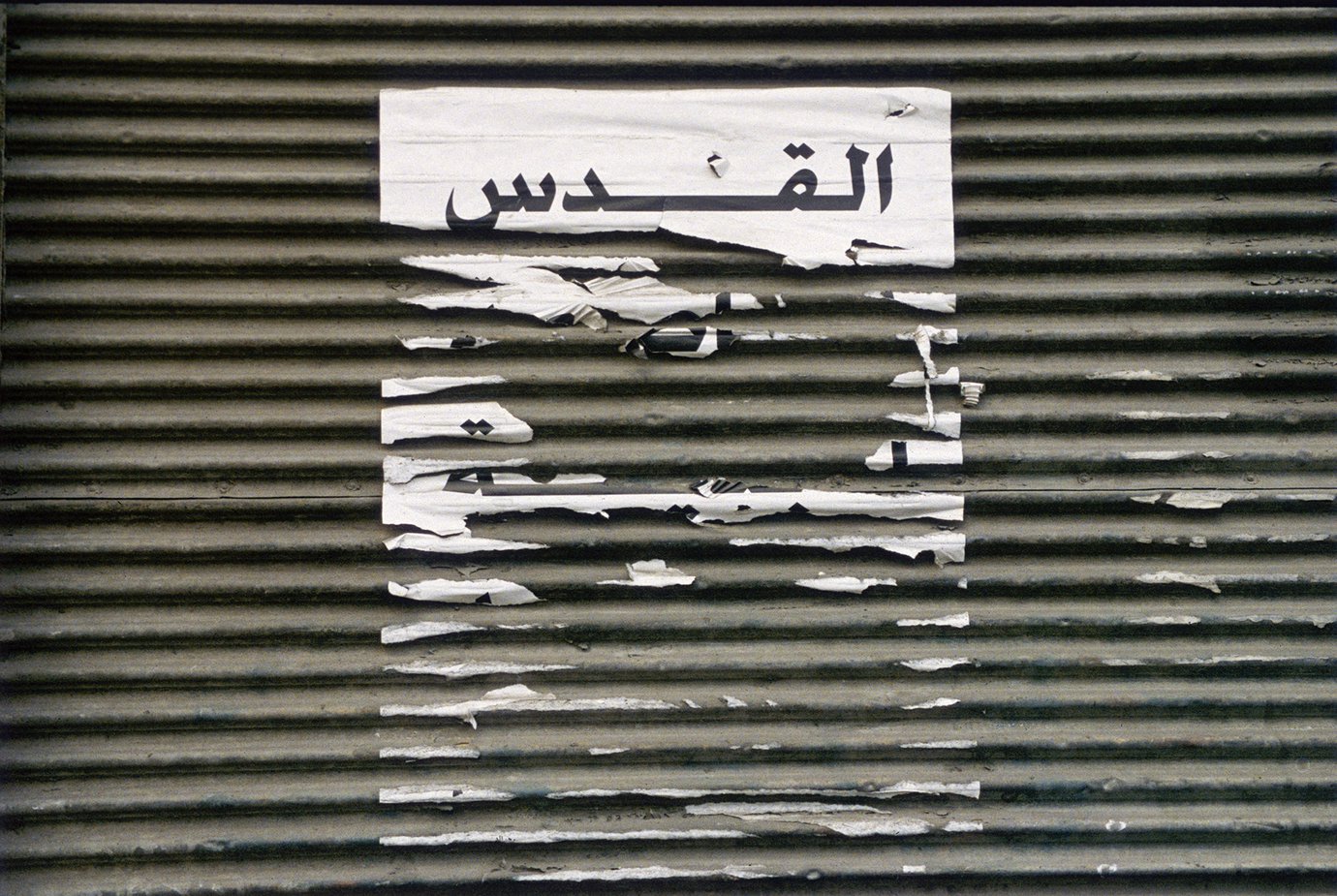 Picture of shredded paper on a textured background with the word Al Quds in Arabic