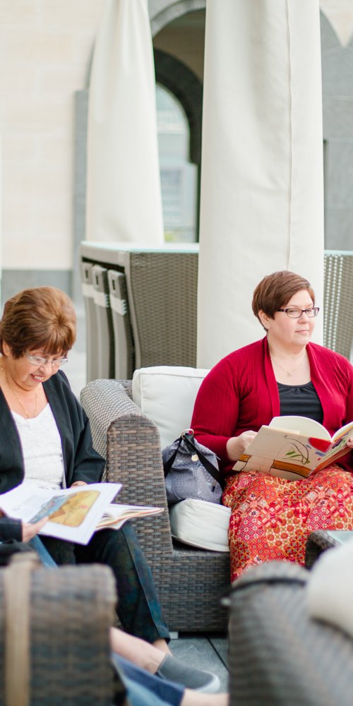 A shot of women sitting at the MIA courtyard with open books in their hands