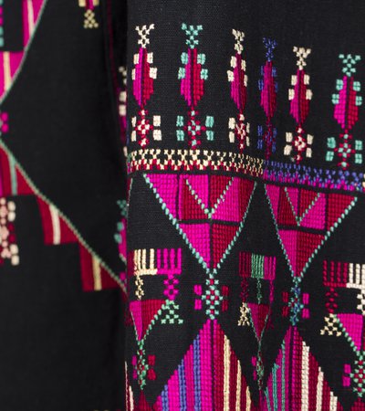 Intricate pink, purple, green and yellow embroidery is shown on rich black material.